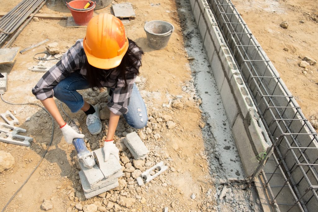 Arbeiter setzt Steine auf Streifenfundament