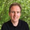 Das Bild zeigt eine Person mit verschwommenem Gesicht vor einem grünen Hintergrund.